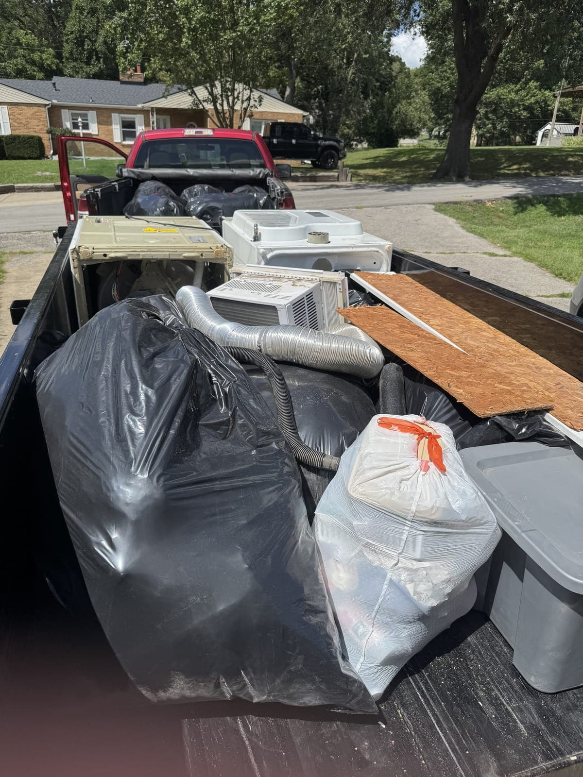 Dump trailer loaded with old window AC units, appliances, and dryer ducting on an appliance-removal job in the Kansas City metro